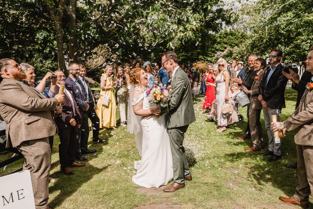 bride ad groom walking down isle laughing at confetti throw